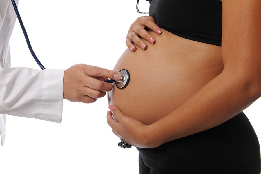 Pregnant woman being examine by a doctor with a stethoscope isol